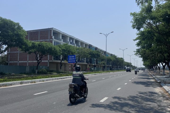 Đại lộ Võ Chí Công nhiều làn xe, dải phân cách cây xanh – một bên là dãy lô đất nền, bên kia là shophouse (ảnh thực tế 10/2026)